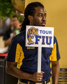 Student holding FIU campus tour sign
